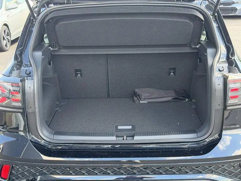 Coffre ouvert vu de l'arrière d'un Volkswagen T-Cross noir, montrant un intérieur de coffre vide avec un petit sac noir.