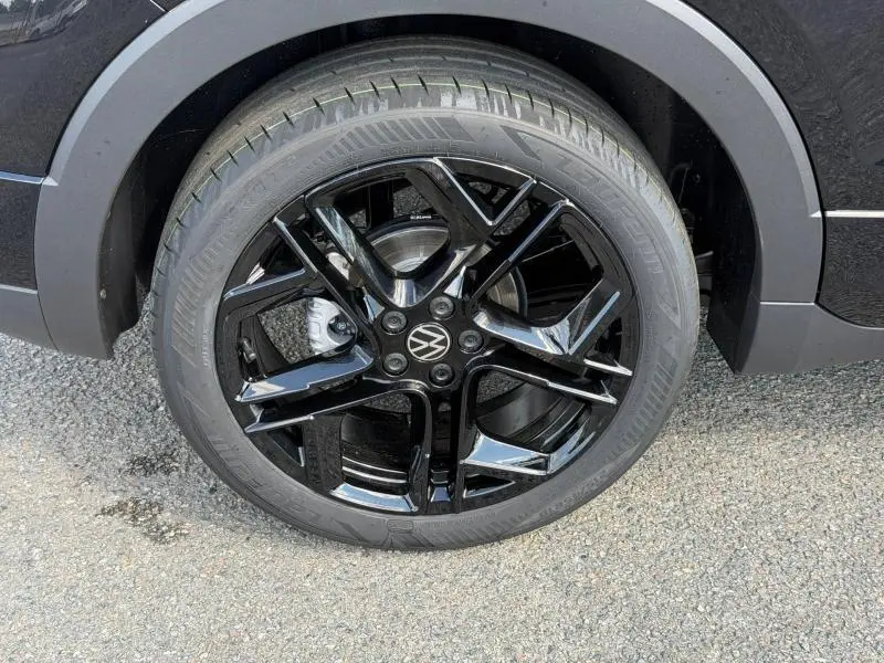 Gros plan sur la jante noire brillante du côté arrière droit d'un Volkswagen T-Cross 2026 noir.