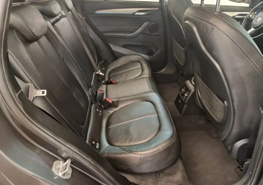Vue intérieure arrière côté gauche du BMW X1 sDrive18i M Sport 2019 avec sièges cuir noirs et finitions soignées