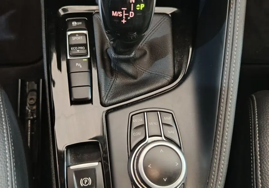 Gros plan sur la console centrale noire brillante du BMW X1 sDrive18i M Sport 2019 avec levier de vitesse automatique et molette de contrôle.