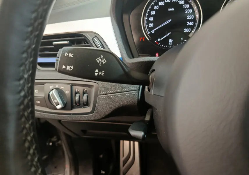 Gros plan sur la commande de clignotant et le tableau de bord noir du BMW X1 sDrive18i M Sport 2019.