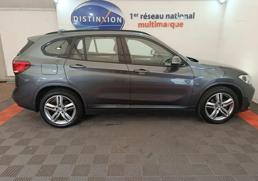BMW X1 sDrive18i M Sport gris métallisé vu de profil côté gauche dans un showroom multimarque
