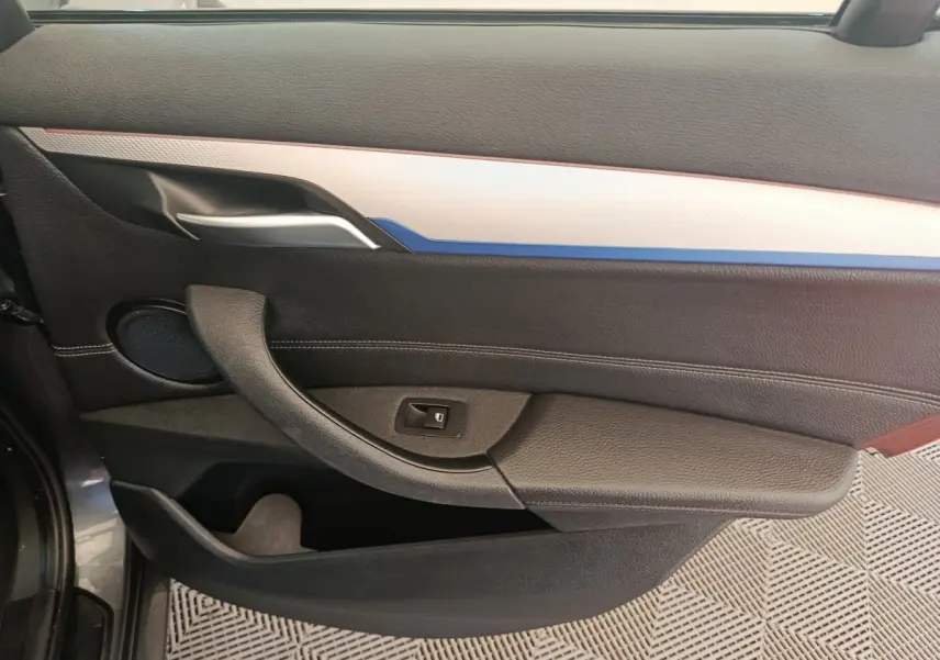 Panneau de porte côté gauche noir avec insert blanc et bleu, poignée argentée, haut-parleur rond visible.