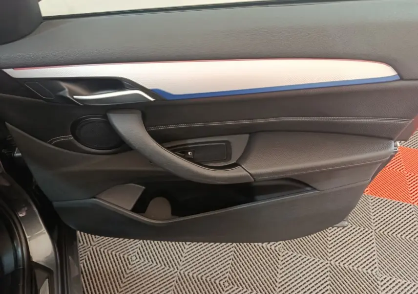Vue latérale du panneau de porte avant gauche noir avec insert blanc et bleu sur BMW X1 sDrive18i M Sport 2019.