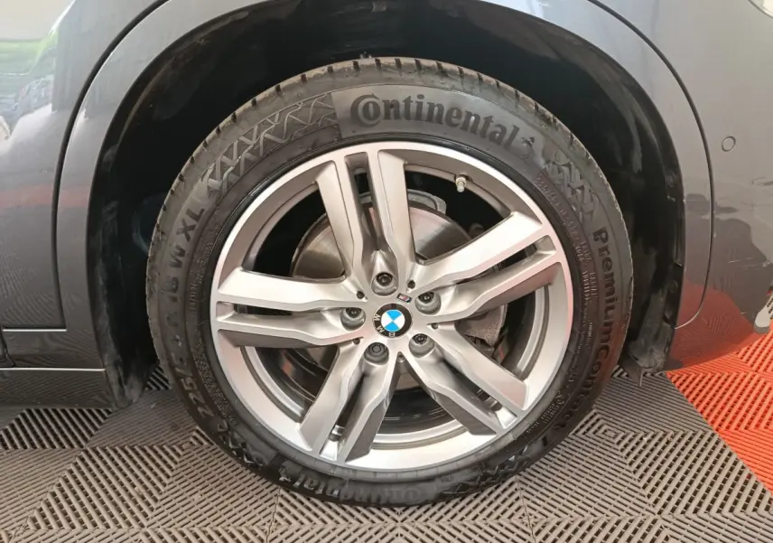 Gros plan sur la roue avant gauche d'un BMW X1 sDrive18i M Sport gris avec jante alliage et pneu Continental.