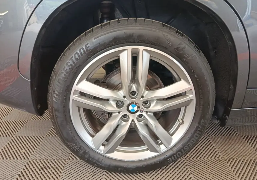 Gros plan sur la roue avant gauche du BMW X1 sDrive18i M Sport 2019 avec jante alliage argentée et pneu Bridgestone.