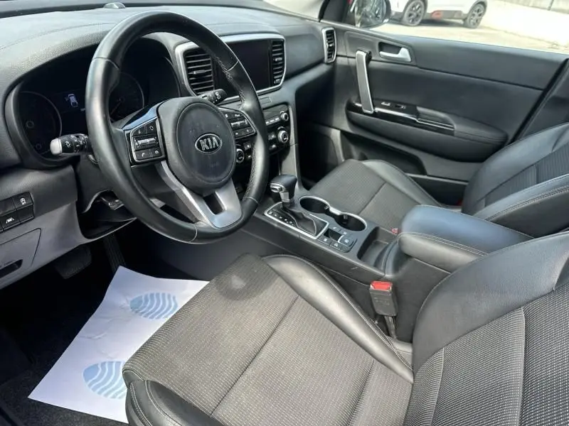 Intérieur noir du Kia Sportage 2021 vu côté conducteur, avec volant multifonction et console centrale moderne.