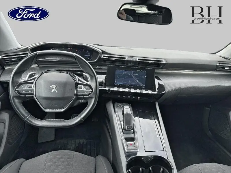 Vue intérieure du tableau de bord et volant cuir noir de la Peugeot 508 SW 2020 avec écran tactile et inserts carbone.