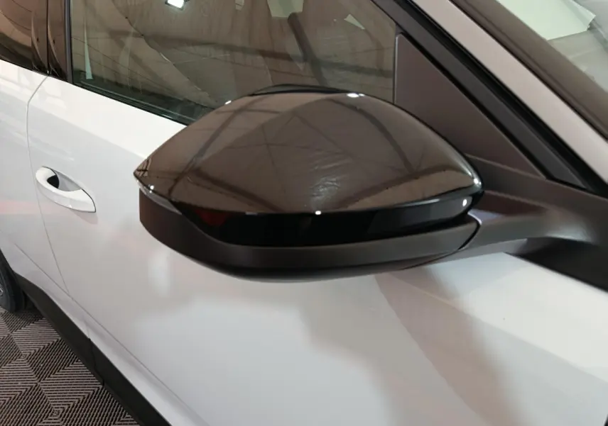 Rétroviseur noir en gros plan côté gauche sur Peugeot 3008 blanc, avec poignée de porte visible en arrière-plan.