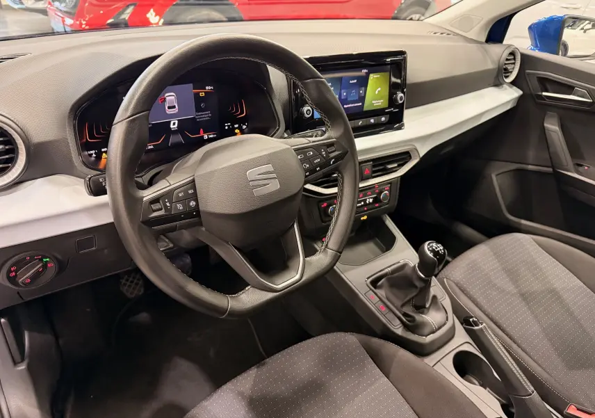 Vue intérieure côté conducteur de la SEAT Ibiza 1.0 TSI 95CH Copa 2025 avec volant multifonction, écran tactile et boîte manuelle.