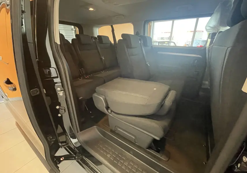 Vue intérieure côté gauche du Peugeot Traveller noir, montrant les sièges arrière avec un siège central partiellement relevé.