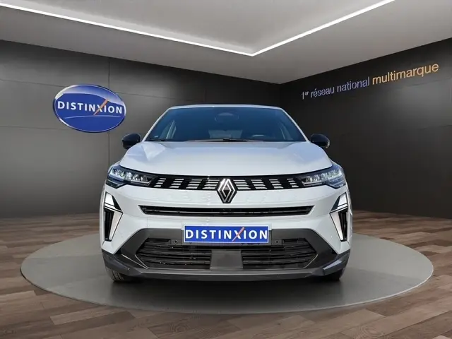 Vue frontale de la Renault SYMBIOZ gris clair 2025 en showroom avec éclairage moderne et logo Distinxion visible.