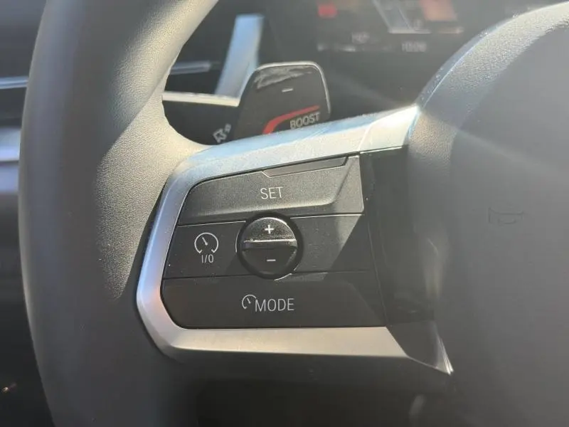 Gros plan sur les commandes de régulateur de vitesse au volant cuir d'une BMW X2 Skyscraper Grey 2025.