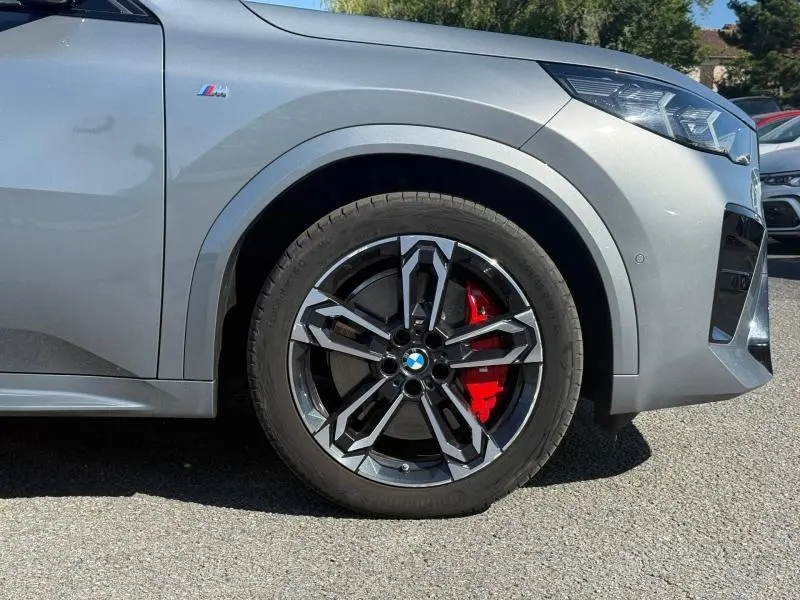 Gros plan sur la roue avant droite d’un BMW X2 gris Skyscraper métallisé avec étrier de frein rouge et logo M Sport.