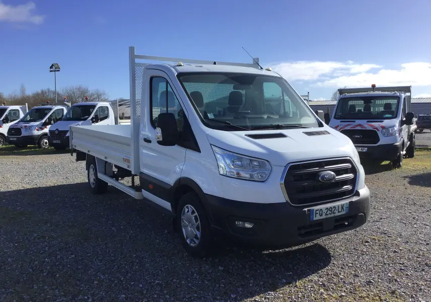 Ford Transit Chassis Cabine blanc en 3/4 avant droit, avec plateau 4 mètres et ridelles en aluminium visibles.
