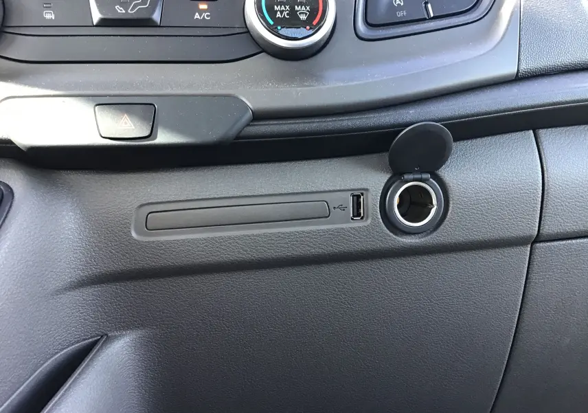 Détail de la console centrale du Ford Transit Chassis Cabine 2020 montrant la prise USB et l'allume-cigare avec couvercle ouvert.