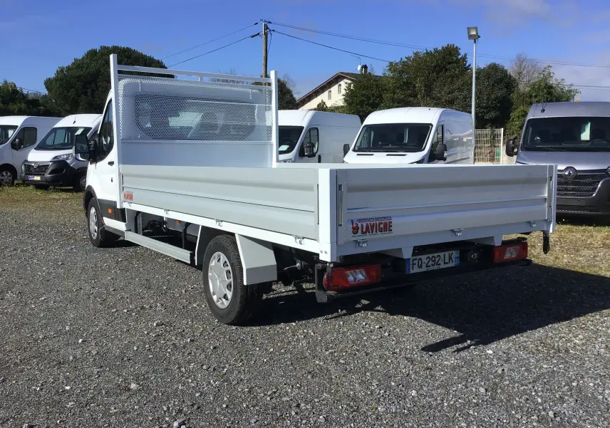 Vue 3/4 arrière droite d'un Ford Transit Chassis Cabine blanc avec plateau 4 mètres et ridelles aluminium.