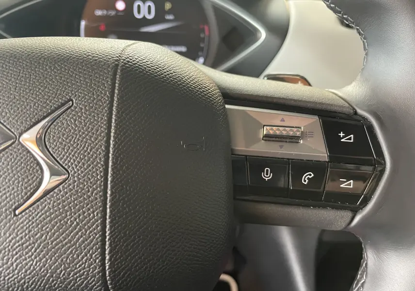 Gros plan sur le volant en cuir noir du DS3 Crossback 2024, avec commandes vocales et de volume intégrées.
