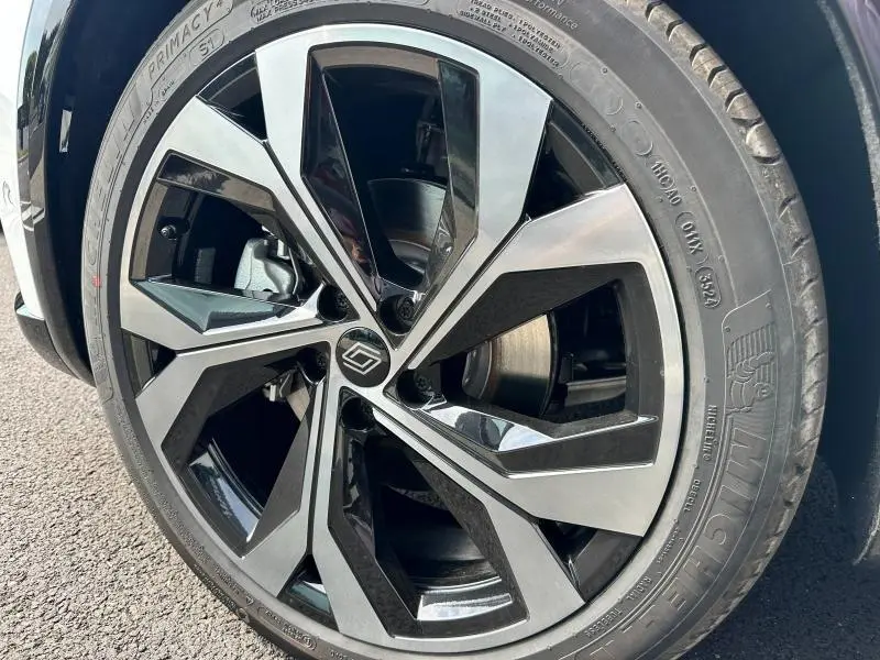 Gros plan sur la jante alu bicolore noire et grise du côté avant droit du Renault Austral gris 2025 hybride.