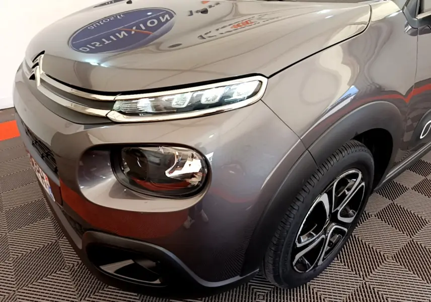 Vue 3/4 avant droit d'une Citroën C3 2019 gris foncé avec phares LED et jantes noires distinctives.