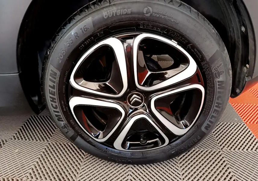 Gros plan sur la jante noire et argentée Michelin d'une Citroën C3 gris foncé, mettant en valeur le logo Citroën central.