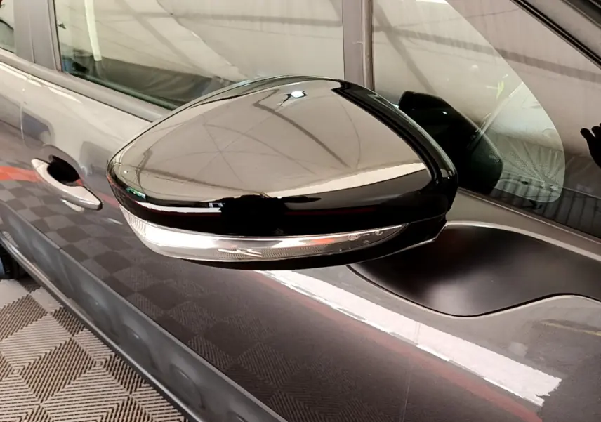 Rétroviseur noir brillant côté gauche d'une Citroën C3 gris foncé vue de profil rapproché.