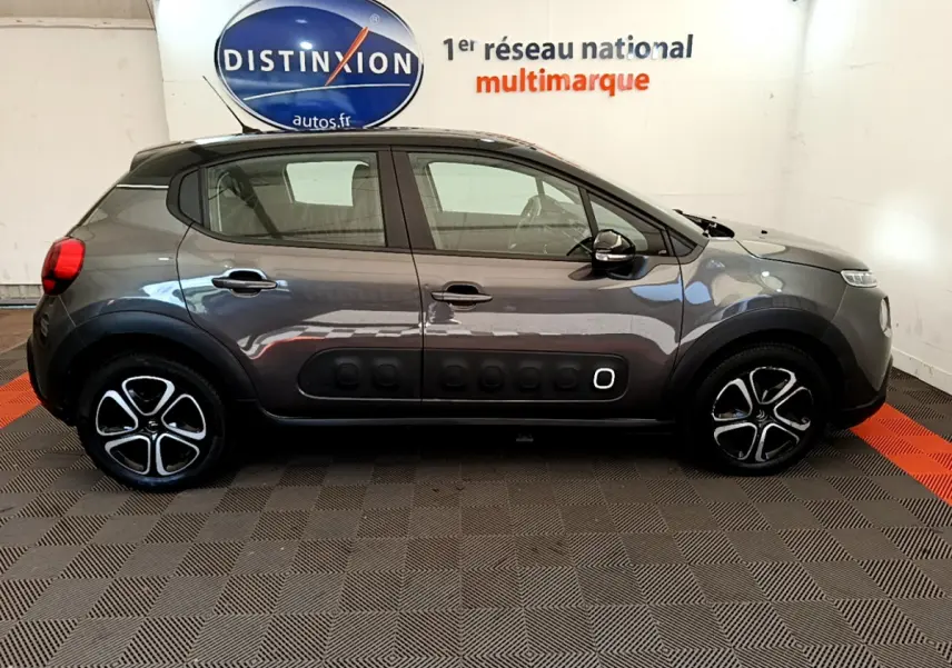 Profil côté droit d'une Citroën C3 gris foncé 2019 avec protections latérales noires et jantes stylisées.