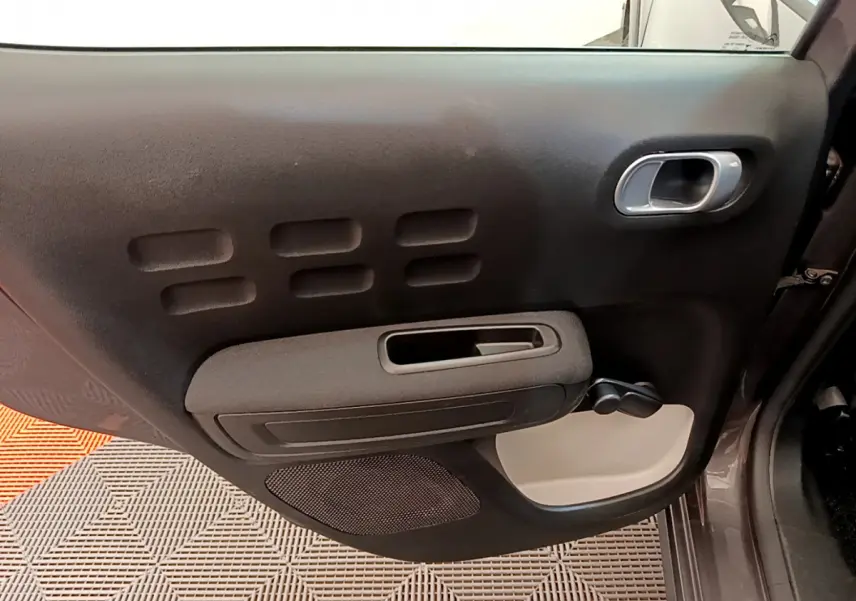 Vue intérieure du panneau de porte avant droit gris foncé de la Citroën C3 2019 avec poignée et commande manuelle de vitre