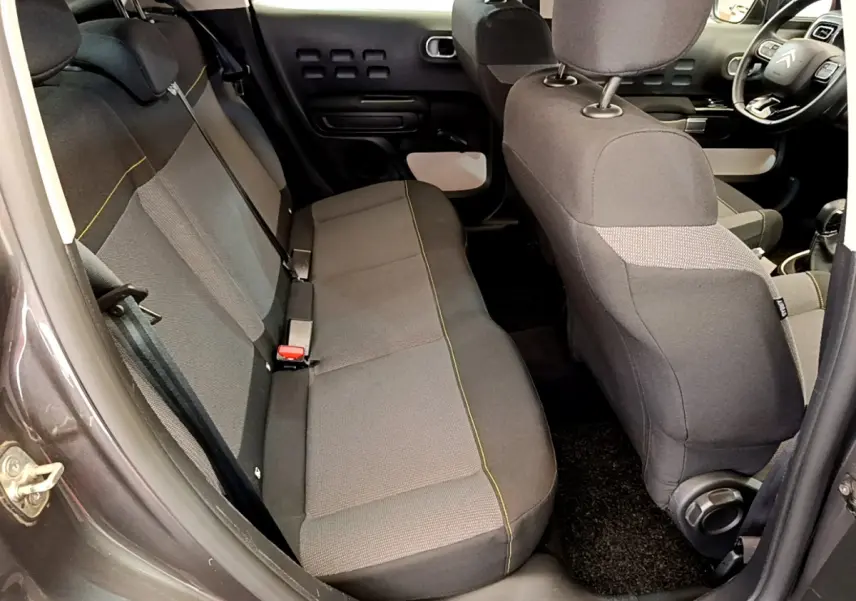 Vue intérieure côté gauche arrière de la Citroën C3 gris foncé, montrant la banquette arrière et l'avant du siège conducteur.
