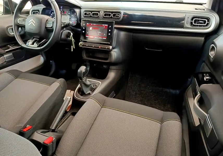 Intérieur de la Citroën C3 gris foncé, vue côté conducteur, tableau de bord avec écran tactile central et volant multifonctions cuir.