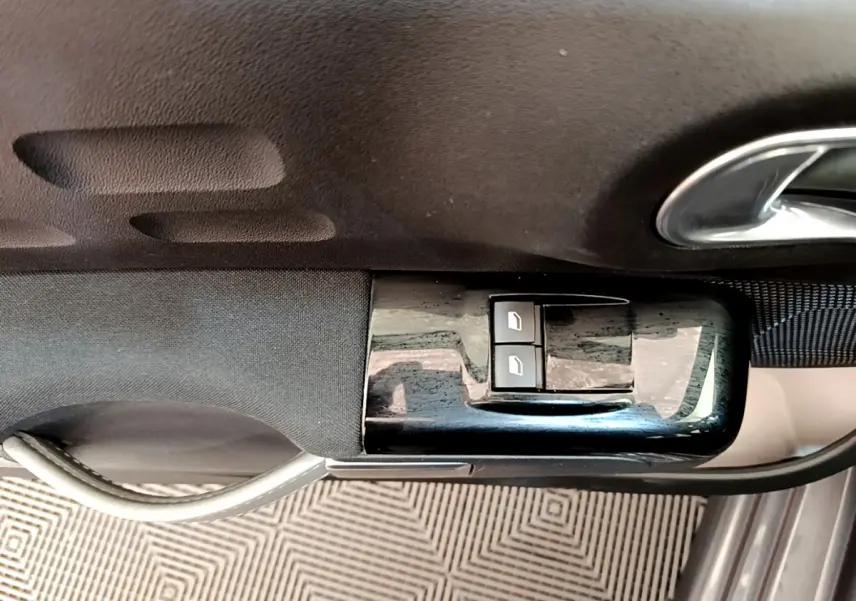 Gros plan sur la commande des vitres électriques côté conducteur d'une Citroën C3 gris foncé, finition Shine 2019.