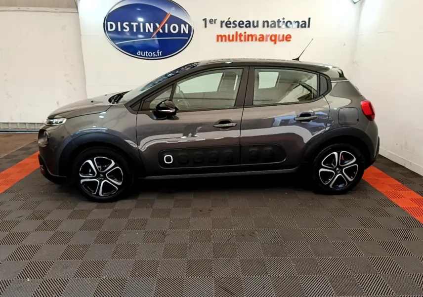 Profil côté gauche d'une Citroën C3 gris foncé 2019 avec protections latérales noires et jantes stylisées en concession.
