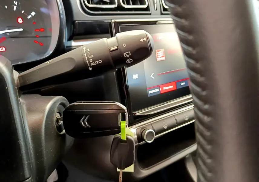 Gros plan sur le volant et le commodo gauche de la Citroën C3 gris foncé, avec clé insérée et écran tactile visible.