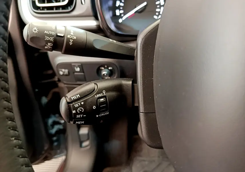 Gros plan sur le volant cuir et les commandes de régulateur de vitesse d'une Citroën C3 gris foncé, version Shine 2019.