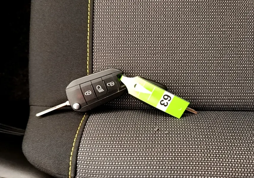 Clé de contact noire posée sur un siège avant gris foncé à surpiqûres jaunes d'une Citroën C3 PureTech 2019.