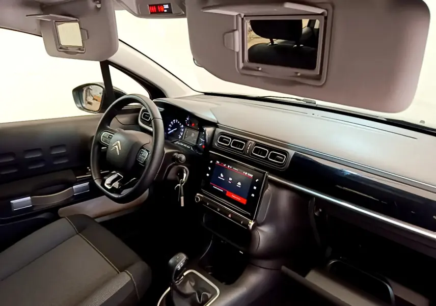 Intérieur de la Citroën C3 2019 vu côté conducteur, tableau de bord noir avec écran tactile central et volant cuir.