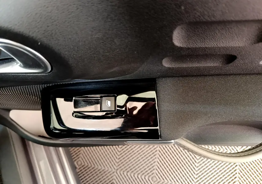 Détail de la commande de lève-vitre côté conducteur sur la porte intérieure noire d'une Citroën C3 gris foncé 2019.