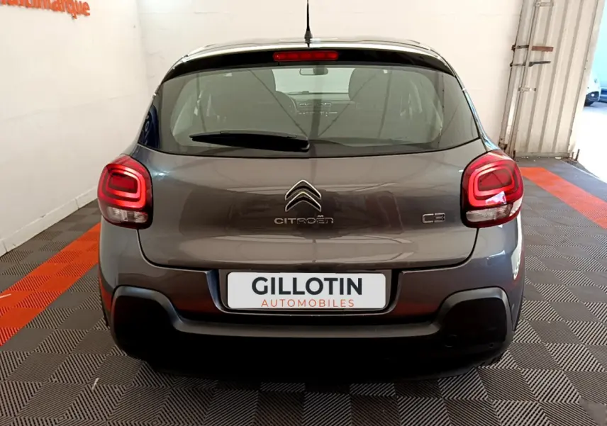 Vue arrière d'une Citroën C3 gris foncé avec feux arrière LED et logo centré sur un sol à damier noir et rouge.