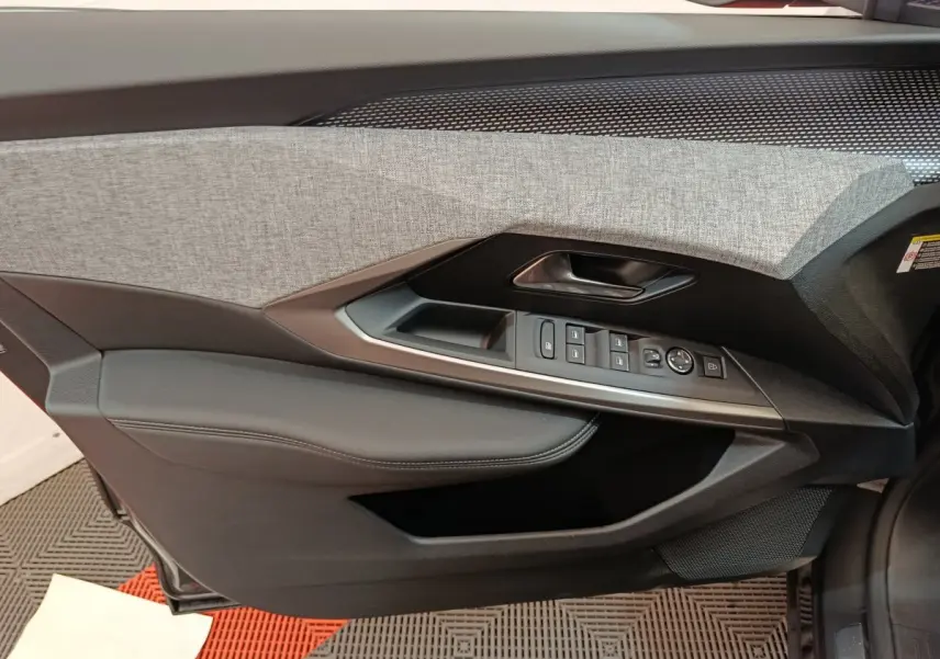 Panneau de porte côté conducteur du Peugeot 3008 noir 2025, avec commandes électriques et garniture tissu gris.