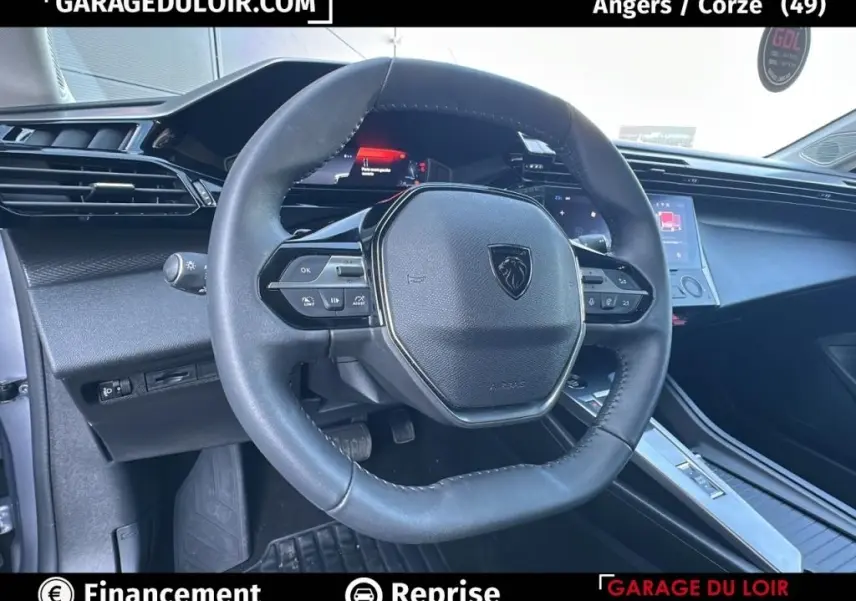 Vue intérieure centrée sur le volant cuir multifonctions de la Peugeot 308 gris clair avec tableau de bord digital.