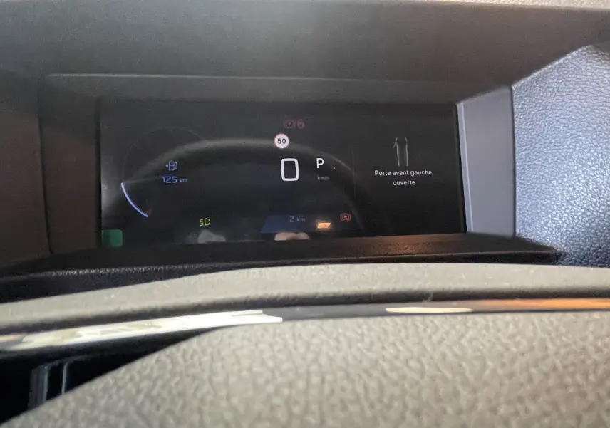 Vue rapprochée du tableau de bord numérique du Peugeot Traveller noir, affichant la porte avant gauche ouverte et l'autonomie restante.