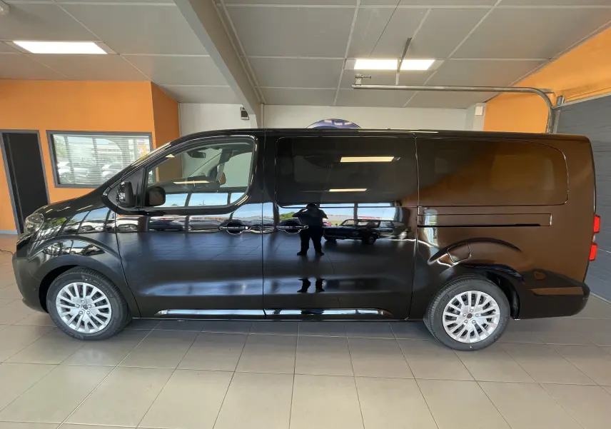 Vue latérale droite du Peugeot Traveller noir 2026 en intérieur, soulignant ses grandes portes coulissantes et ses jantes alliage.