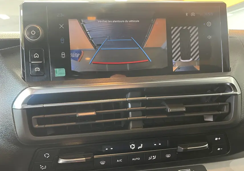 Vue rapprochée de l'écran tactile du Peugeot Traveller 2026 noir montrant la caméra de recul et les commandes de climatisation.