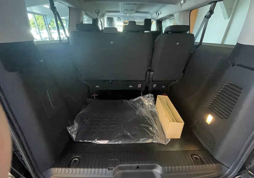 Vue intérieure du coffre arrière du Peugeot Traveller noir 2026, avec sièges rabattus et éclairage latéral allumé.