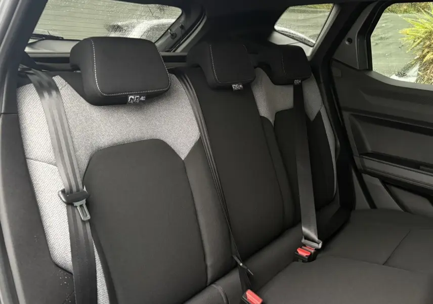 Vue intérieure des sièges arrière du Dacia Duster 2026, tissu noir et gris avec ceintures de sécurité visibles.