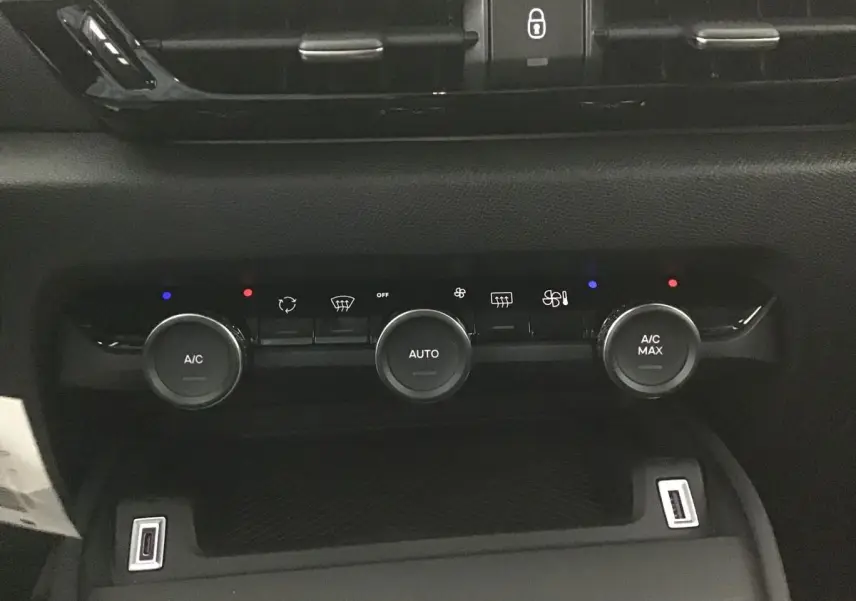 Vue rapprochée du tableau de bord noir de la Citroën C4 2022, mettant en valeur les commandes de climatisation et ports USB.
