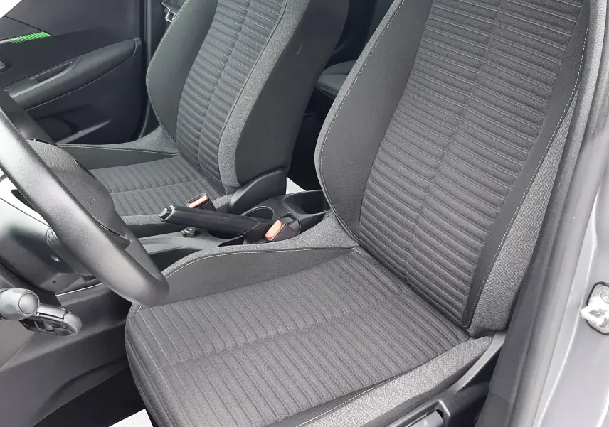 Vue intérieure rapprochée des sièges avant en tissu gris foncé de la Peugeot 208 2024, porte ouverte côté conducteur.