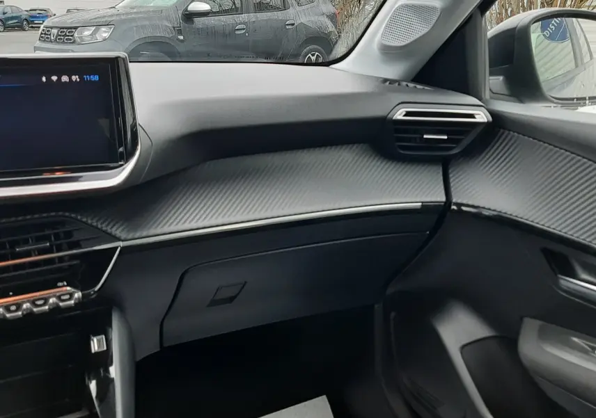 Vue intérieure côté passager de la Peugeot 208 2024, tableau de bord gris avec finition texturée et écran tactile.