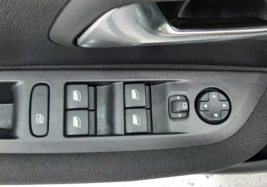 Gros plan sur la commande de lève-vitres et réglage des rétroviseurs côté conducteur d'une Peugeot 208 gris selenium.