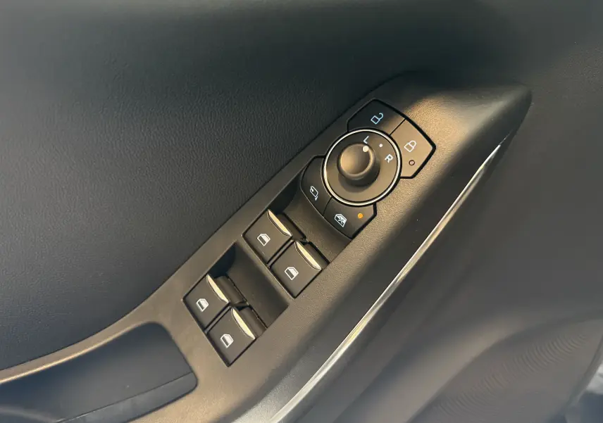 Gros plan sur les commandes de lève-vitres et rétroviseurs côté conducteur d’une Ford Puma noir Agate 2022.